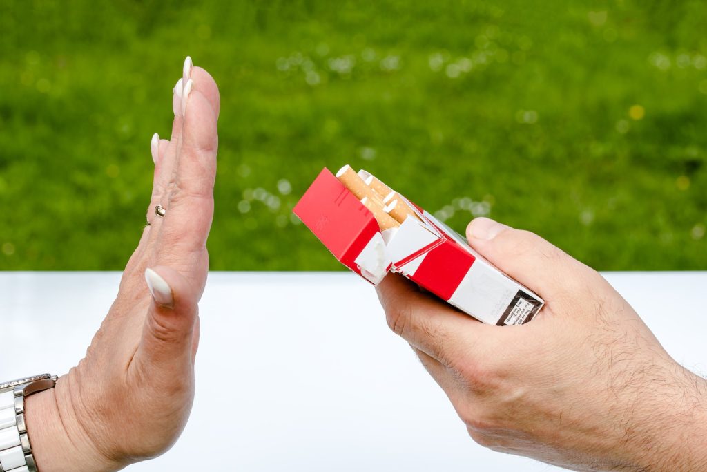 image of female hand resisting a pack of cigarettes r/t healthy lifestyle.