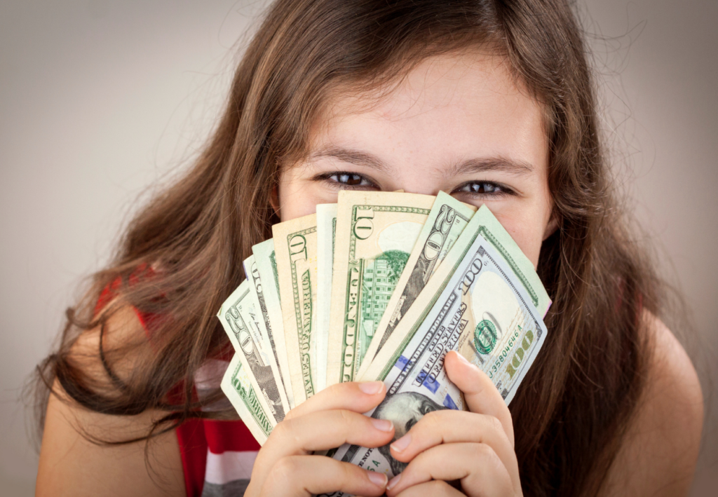 Closeup of young girl holding a fan of money r/t teaching kids about money.