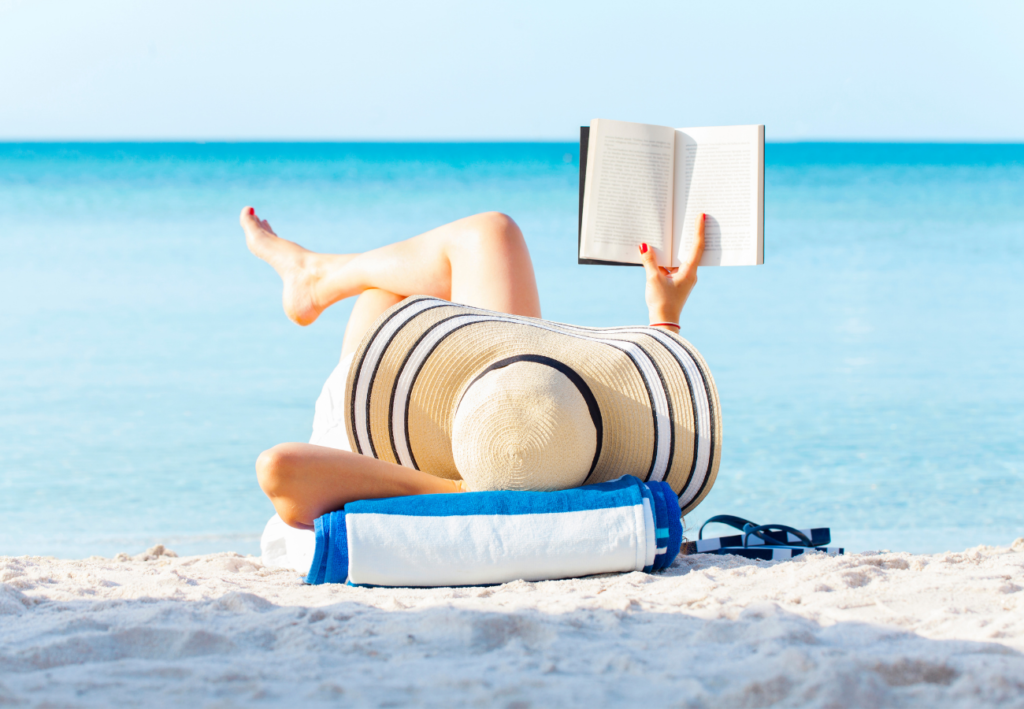 Lady relaxing on beach reading books