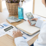 Women at desk holding money r/t financially recover