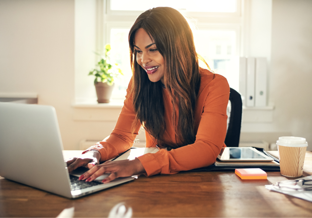 Woman at smiling while using laptop r/t fresh start.